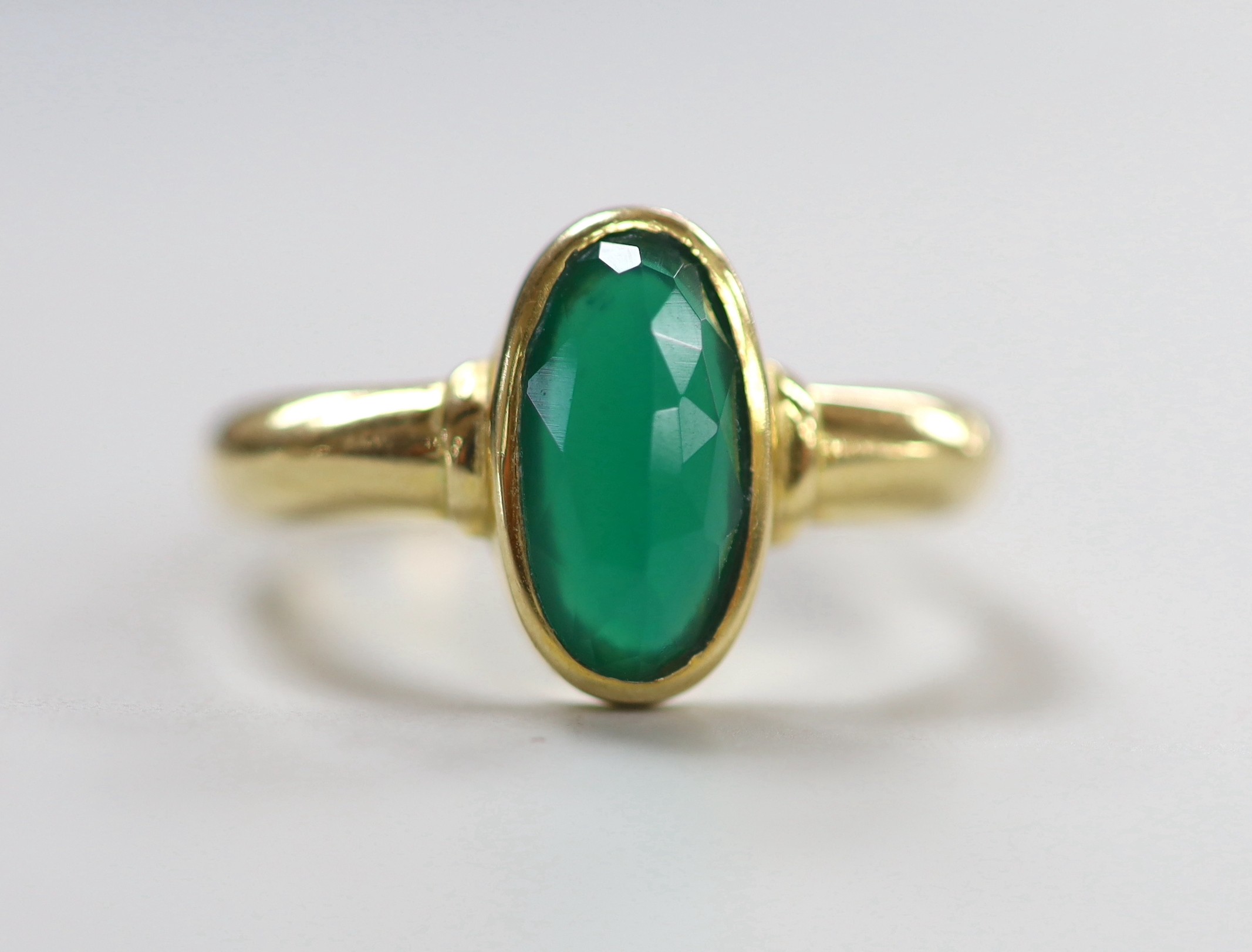 A modern yellow metal and single stone facetted oval chrysoprase set ring, size S, gross weight 3.7 grams.